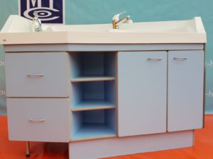Maximat  Säuglingspflegekombination für die Klinikeinrichtung . Eine Wickelkommodeumrahmt von einem Handwaschbecken und einer ergonomischen Badewanne